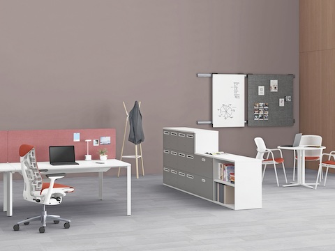 Ein Paragraph Storage-Gerät teilt den Platz in einem offenen Büro und trennt Layout Studio-Benching von einem runden Everywhere Table für schnelle Zusammenarbeit.