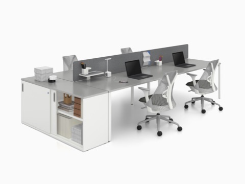 Un'unità di archiviazione Paragraph contenente libri e raccoglitori estende una configurazione di panca Layout Studio con sedie Sayl grigie. Un'unità di archiviazione Paragraph contenente libri e raccoglitori estende una configurazione di panca Layout Studio con sedie Sayl grigie.