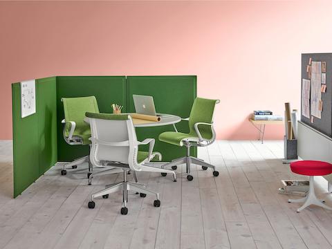 Four green fabric Pari freestanding privacy screens connected in a L-shape configuration with three Setu chairs and a circular Setu table in it.