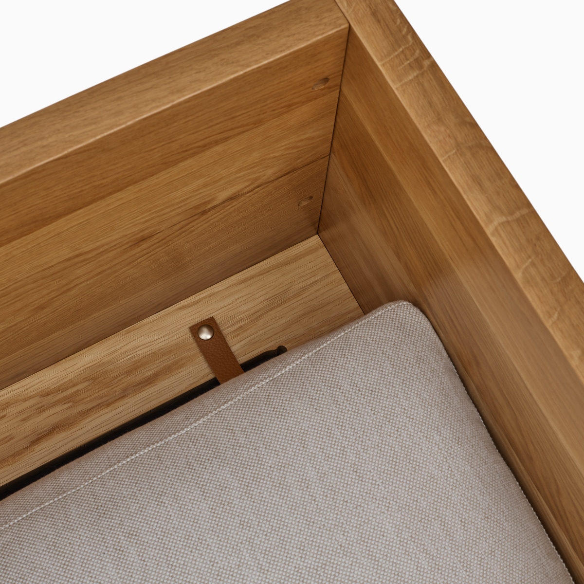 A detail view of the Pawson Drift Sofa Group's leathe strap that connects the cushion to the oak frame.