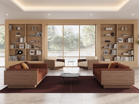 Pawson Drift Sofa Group in walnut with sienna textile cushions and white leather cushions near an oak bookcase in a hotel lobby