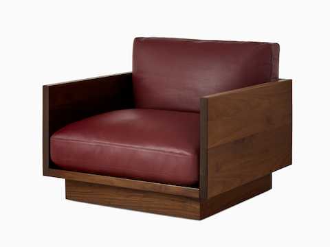 Front view of the Pawson Drift Sofa in walnut and grey cushions, and the Lounge Chair in a maroon leather cushion.