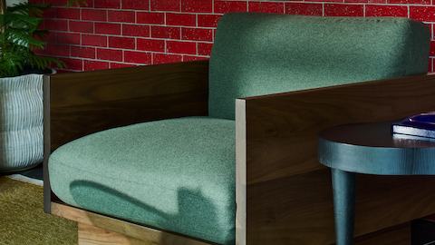 Green Pawson Drift Lounge Chair with walnut frame near red tiles