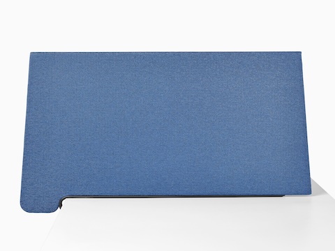 Perfil lateral de una pantalla lateral personal trapezoidal en tela azul sujetada a una superficie de trabajo en blanco.