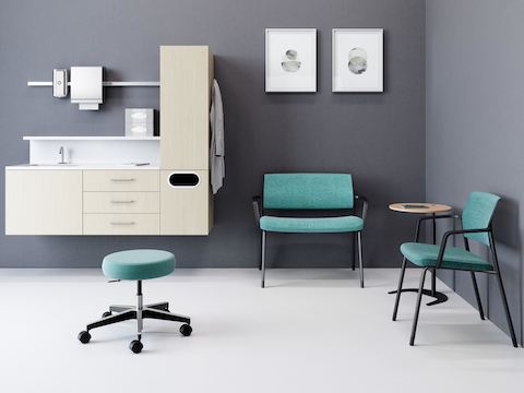 Exam Room with a teal upholstered Physician Stool, light finish wall-hung Mora System, and two green Verus wall-saving side chairs.