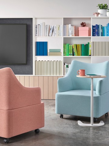 Two Plex club chairs with salmon and light blue upholstery face each other with a height-adjustable work table between.