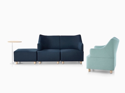 A Plex setting featuring a work table, dark blue ottoman and loveseat, and light blue club chair.