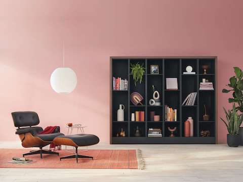 Port Storage System with a wooden frame and black shelves being used as a decorating cabinet, next to a Nelson Bubble Lamp and an Eames Lounge Chair and Ottoman.