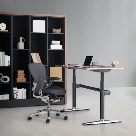 Port Storage System with a wooden frame and black shelves behind an Atlas height-adjustable desk with an Aeron Chair. Port Storage System with a wooden frame and black shelves behind an Atlas height-adjustable desk with an Aeron Chair.