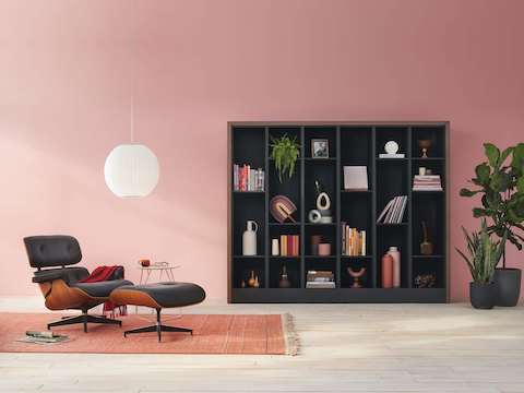 Port Storage System with a wooden frame and black shelves being used as a decorating cabinet, next to a Nelson Bubble Lamp and an Eames Lounge Chair and Ottoman.