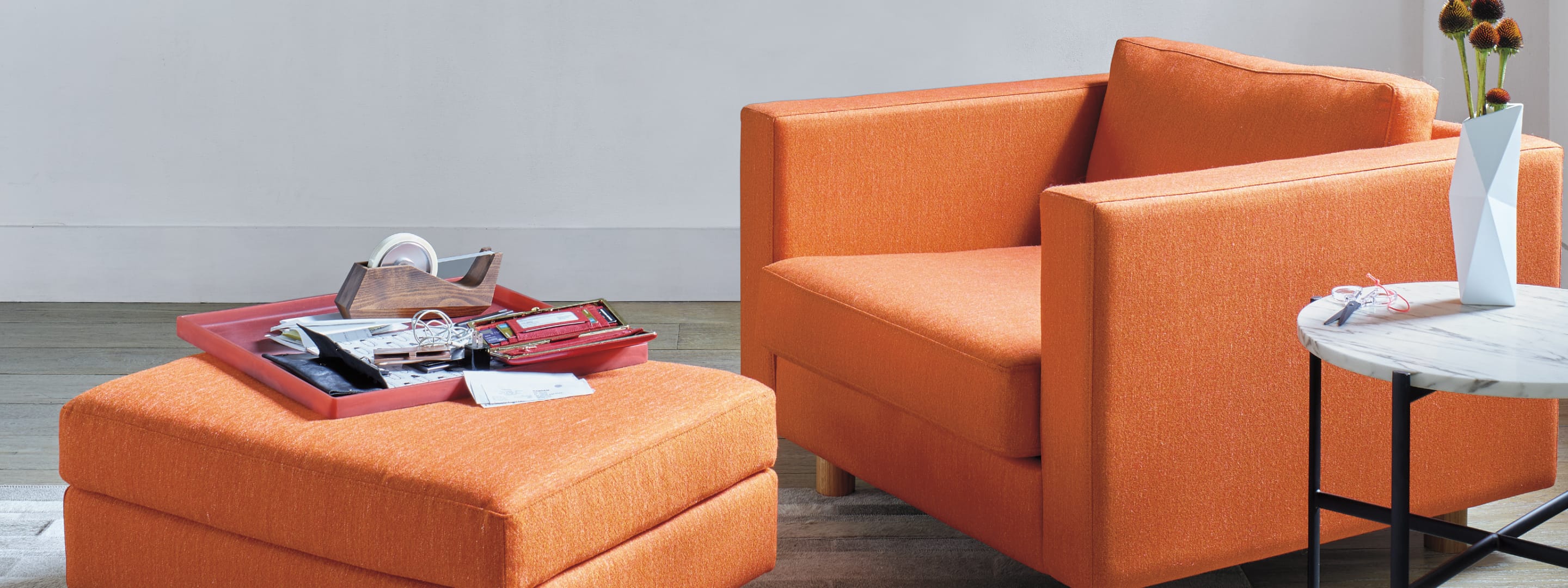 Ein farbenfroher Lispenard Lounge-Sessel und Ottomane in einem Wohnzimmer.