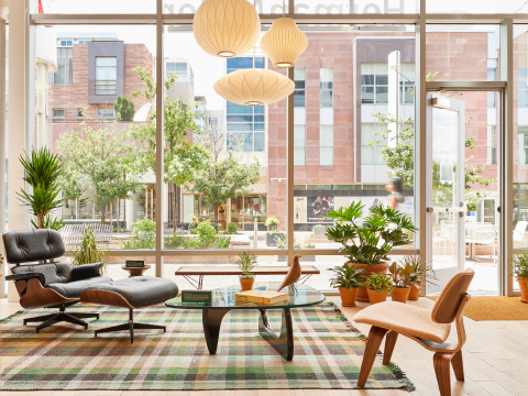 Un sillón lounge Eames, un banco Nelson Cane, una mesa Noguchi y un sillón lounge de madera laminada moldeada Eames en la tienda HM de Cherry Creek, Denver CO.