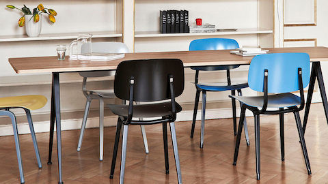 A group of HAY Revolt Chairs around a Pyramid Table with a bookshelf in the background. Select to connect with a certified Herman Miller dealer.