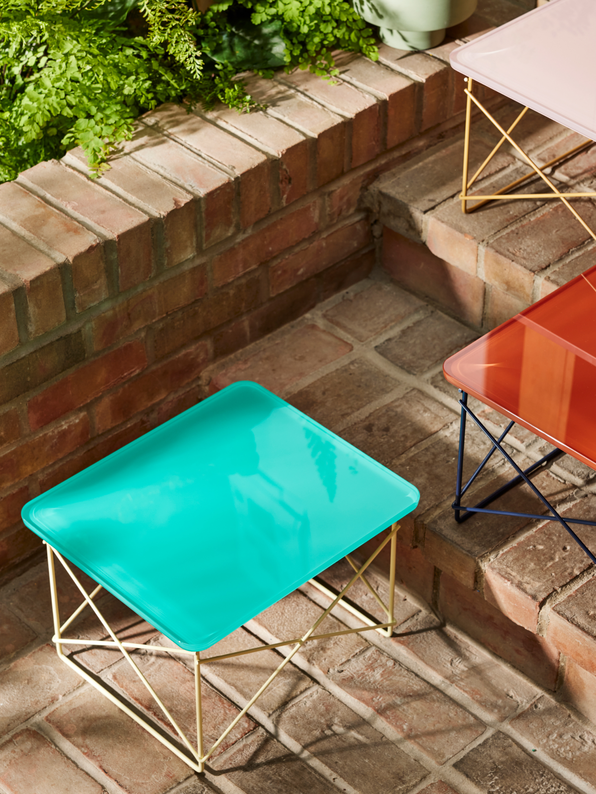 Ambiente exterior con mesa baja con base de alambre de Herman Miller x HAY en color menta.
