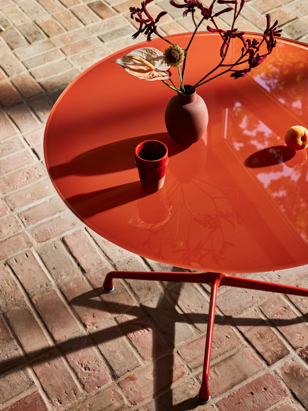 Mesa redonda con base universal Eames de Herman Miller x HAY en rojo hierro.