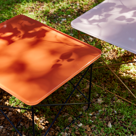 Herman Miller x HAY Eames Wire Base Low Tables in powder pink and iron red.