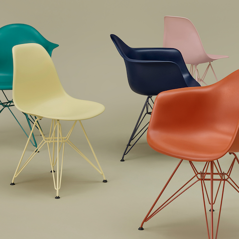 Grupo de sillas de plástico moldeado Eames de Herman Miller x HAY sobre un fondo de color salvia.