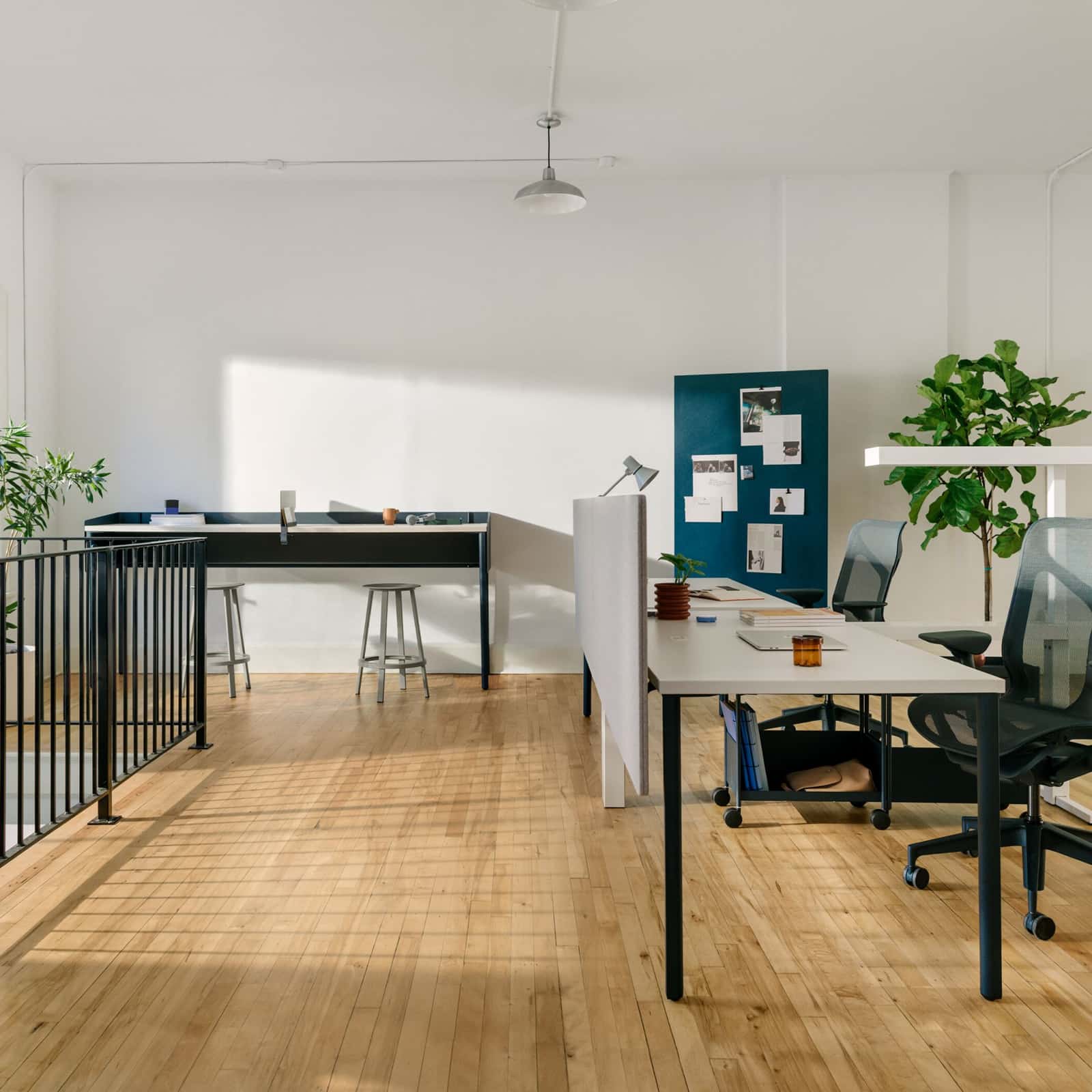 White OE1 Rectangular Tables in a workstations configuration, with a blue OE1 Communal Table and blue OE1 Mobile Easel and project board in the background.