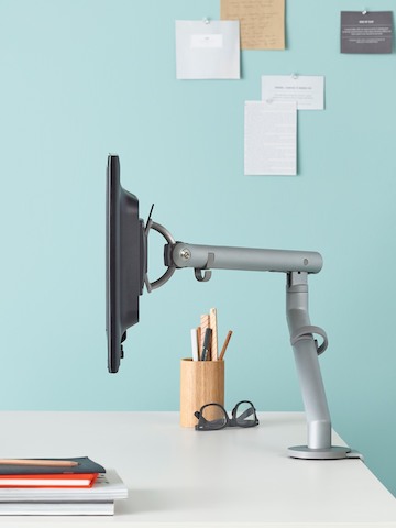 Profile view of a Flo Monitor arm attached to a white desktop.