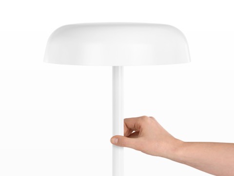 A hand touches the stem of a white Ode Lamp to turn it on or off. A hand touches the stem of a white Ode Lamp to turn it on or off.