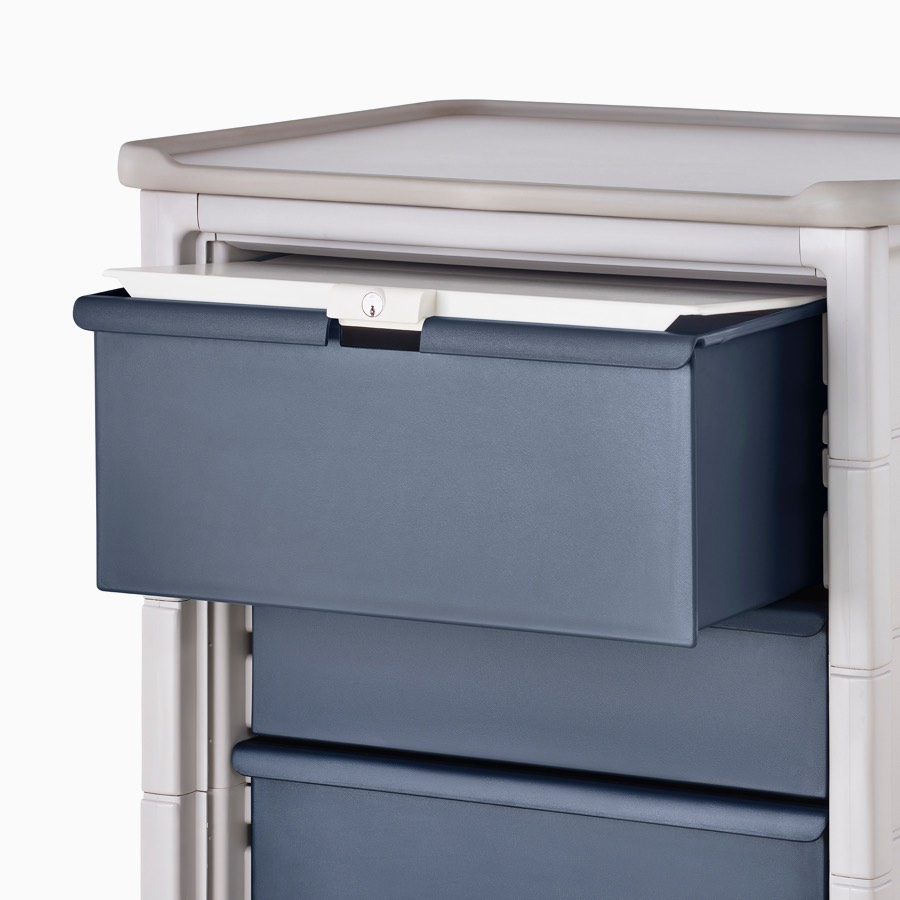 Detail of Procedure and Supply Cart in a light gray body and dark blue modular drawers and a lockable lid.