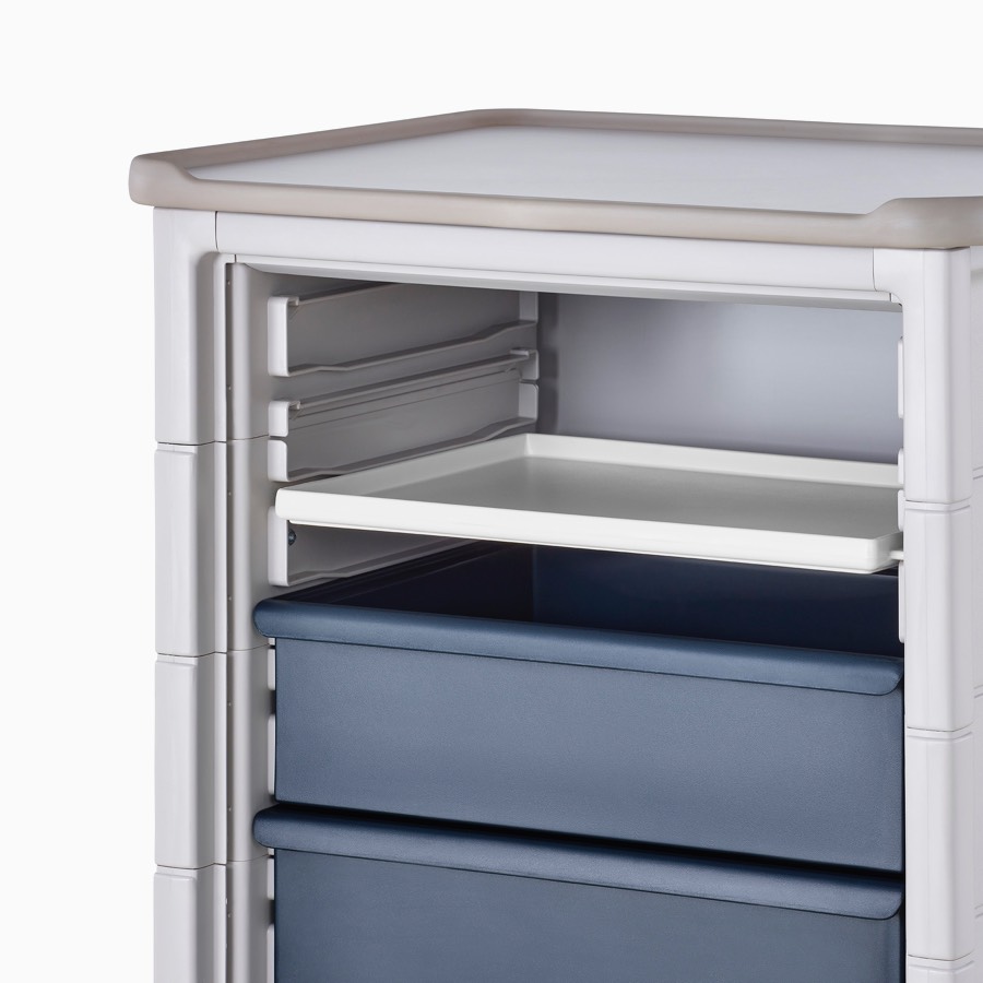 Detail of Procedure and Supply Cart in a light gray body and dark blue modular drawers and a modular interior shelf in soft white.