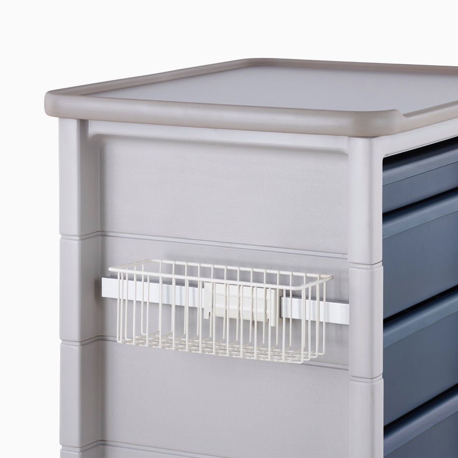 Detail of Procedure and Supply Cart in a light gray body and dark blue drawers and a supply basket hung on the side of the cart's adapter rail.