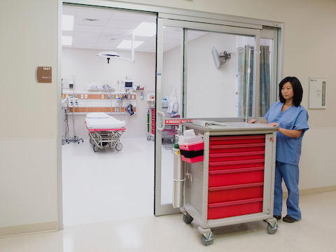 A nurse pushes a mobile Procedure/Supply Cart with seven interchangeable drawers.