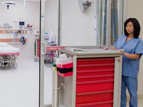 A nurse pushes a mobile Procedure/Supply Cart with seven interchangeable drawers.