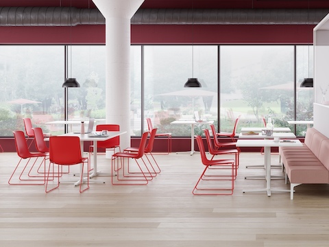Um Café com Cadeiras Empilháveis Pronta vermelhas, Mesas Genus brancas e assentos modulares Naughtone Hatch rosa.