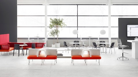 オレンジ、赤、白のPublic Office Landscapeシステムのソーシャルチェアを特徴とするオープンなコラボレーションエリア。
