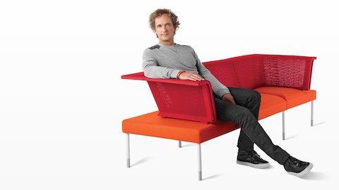 Yves Béhar, leader del team che ha progettato Public Office Landscape, si rilassa sui componenti della sedia sociale rossa e arancione.