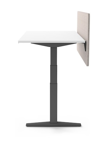 Vue de l’extrémité d'un bureau Ratio à hauteur réglable avec des sous-structures graphite, une surface de travail blanche et un écran de séparation beige sans cadre.