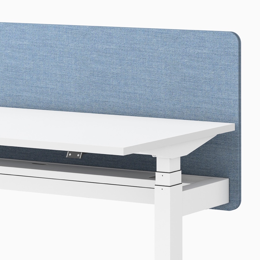 Vista ravvicinata di una scrivania Ratio regolabile in altezza, bianca, con schermo divisorio blu senza telaio.