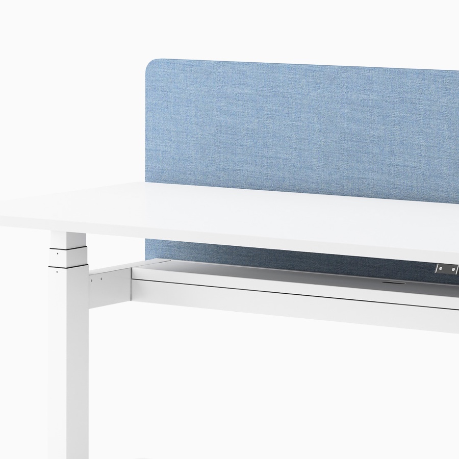 Vista ravvicinata di una scrivania Ratio regolabile in altezza, bianca, con schermo divisorio blu senza telaio.