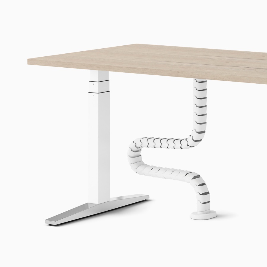 Una scrivania Ratio regolabile in altezza con piano di lavoro in legno e cavo a spirale da pavimento a piano di lavoro.