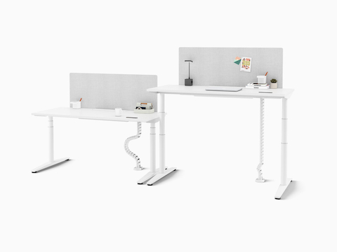 Two Ratio height-adjustable desks in a benching configuration with gray mounted screens. Accessories are found on the desks.