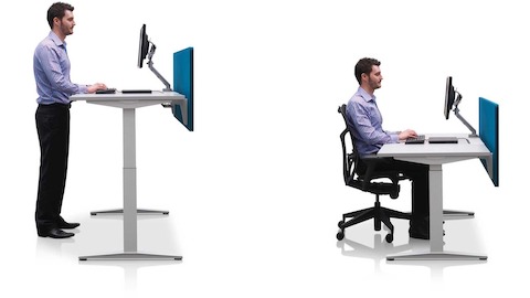 Mesas com ajuste de altura Ratio adjacentes, posicionadas nas alturas para trabalhar sentado e em pé com telas de privacidade azuis.