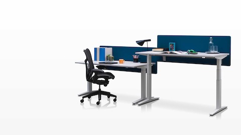 Mesas ajustáveis Ratio adjacentes, posicionadas nas alturas para trabalhar sentado e em pé com telas de privacidade azuis.