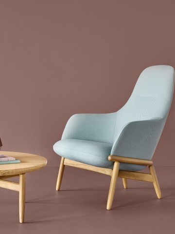 A high-back Reframe Lounge Chair in Saille Celadon, next to a Reframe Table.