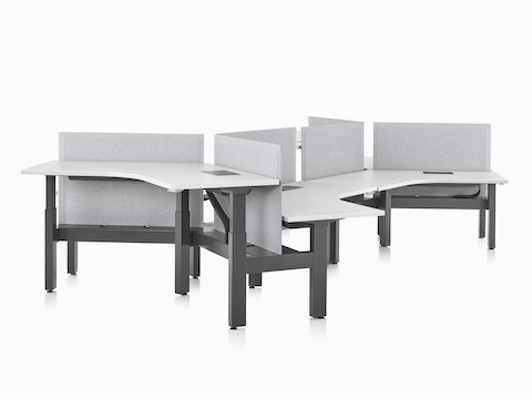 Sistema de mesas com regulagem de altura Renew Link com superfícies de trabalho de 120 graus, pernas pretas e painéis divisores em cinza claro.