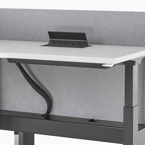 Primer plano de un sistema de escritorios elevados Renew Link con acceso a energía en la superficie de trabajo y organizador de cables por debajo de la superficie. Primer plano de un sistema de escritorios elevados Renew Link con acceso a energía en la superficie de trabajo y organizador de cables por debajo de la superficie.
