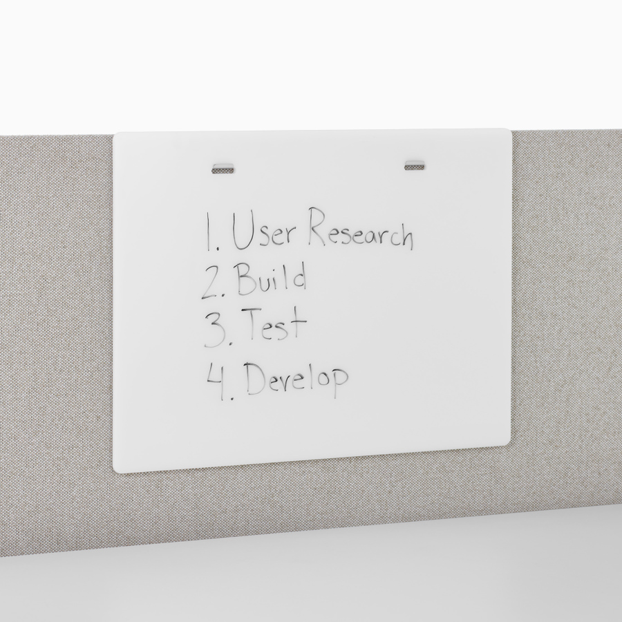 A close-up view of a Renew Link standing desk system's markerboard accessory with writing on it.