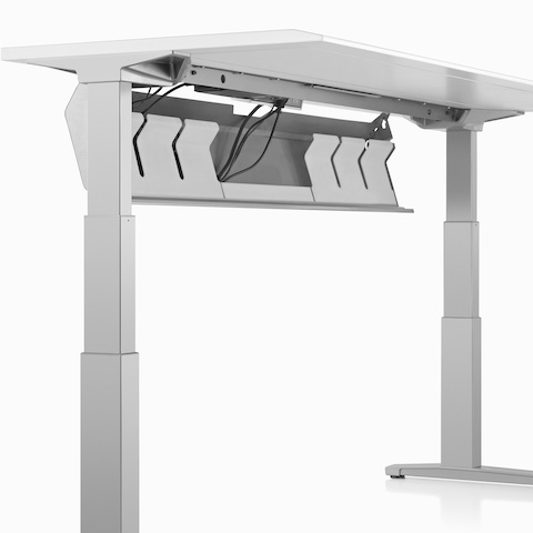 Close-up of an open high-density cable tray holding black cords that's attached to the underside of a Renew Sit-to-Stand Table's work surface. Close-up of an open high-density cable tray holding black cords that's attached to the underside of a Renew Sit-to-Stand Table's work surface.