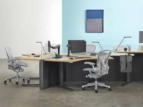 Workstations created with a 120-degree configuration of Canvas Channel, Renew Sit-to-Stand Tables, and light gray Aeron chairs.