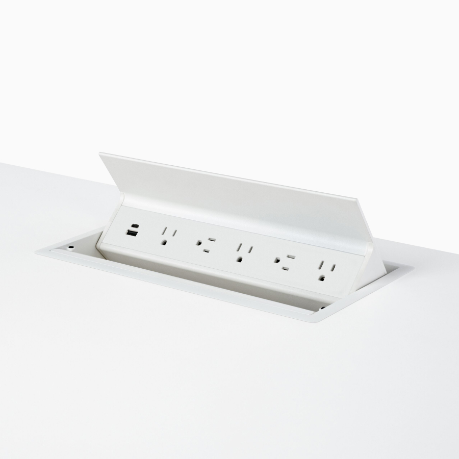 Close-up of an open, white, Logic G1000 power port with two USB connections and five power outlets, integrated in a work surface.