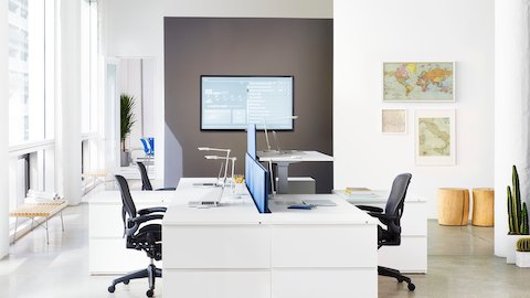 A Renew Sit-to-Stand Table integrated into a cluster of four workpoints with black Aeron office chairs.