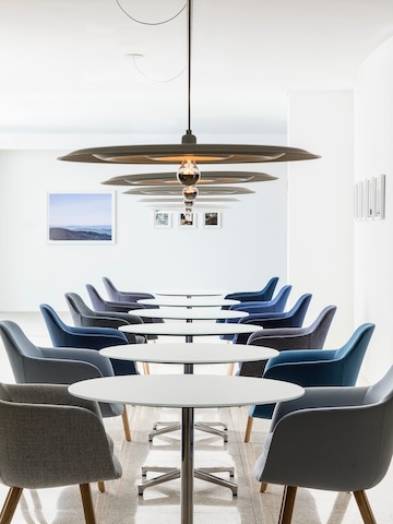 Two facing rows of Saiba Side Chairs in blue and gray upholstery, with round Saiba Tables between.