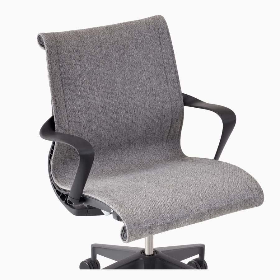 A close-up view of an upholstered Setu chair with arms in gray.