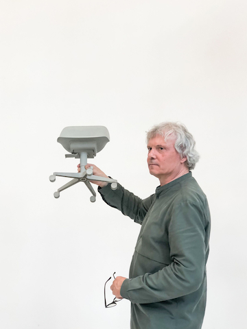Burkhard Schmitz from Studio 7.5 holding a scale model of the Zeph chair.